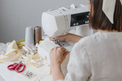 Midsection of woman using sewing machine