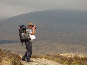 Man photographing while standing on mountain road