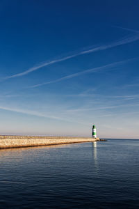 Lighthouse by sea against sky