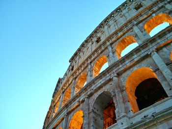 Low angle view of coliseum against clear blue sky