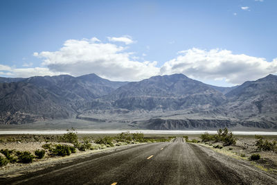 Road by mountains against sky