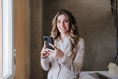 Professional confident architect woman in construction site using mobile phone. home renovation