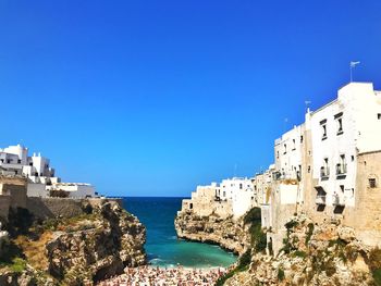 Buildings by sea against blue sky