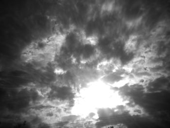 Low angle view of sunlight streaming through clouds