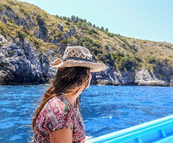 Woman wearing hat against sea and mountains