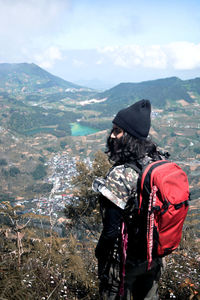 Rear view of man looking at mountains against sky
