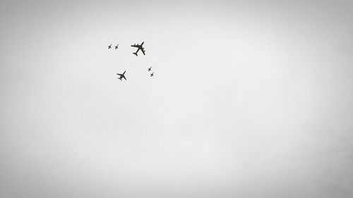 Low angle view of airplanes in mid-air against clear sky
