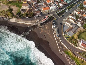 Aerial view of blue ocean water crashing into the black sand beach