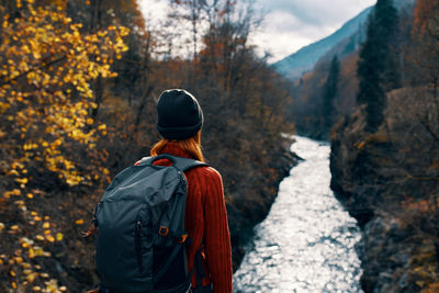 Rear view of man standing by trees during autumn