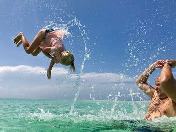 Full length of shirtless man splashing sea against sky