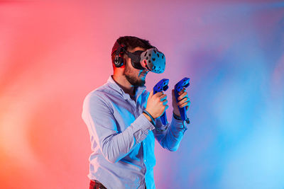 Young man wearing sunglasses standing against blue wall