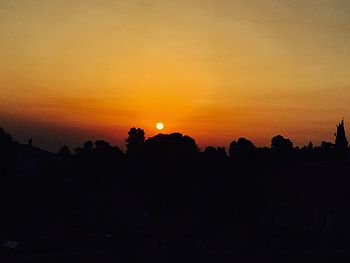 Silhouette trees against orange sky