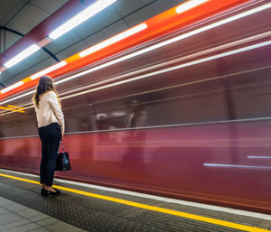 Woman standing by train at railroad station platform