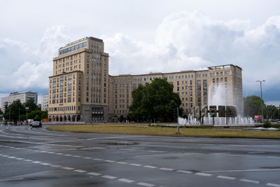 Road by buildings in city against sky