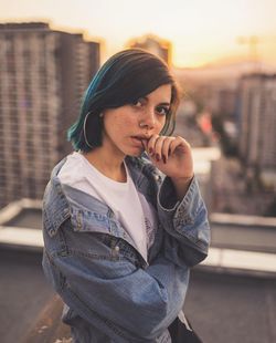 Portrait of young woman in city during sunset