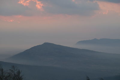 Mountains against cloudy sky at sunrise