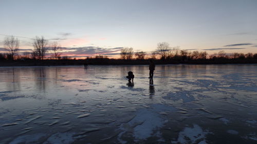 Silhouette person swimming in lake against sky during sunset