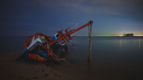 Cranes at beach against sky during sunset