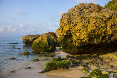 Rock formation on beach against sky