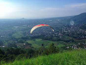 Mid-air paraglider in scenic view of landscape against sky.