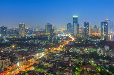 Aerial view of illuminated buildings in city against sky