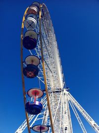 Low angle view of ferris wheel against clear blue sky