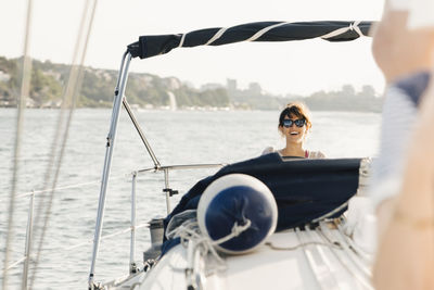 Smiling woman sailing boat in sea against sky