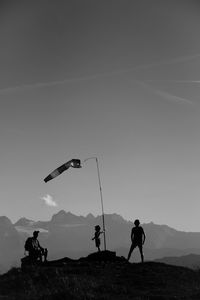 People standing around windsock on mountains against sky