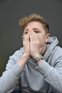 Close-up of teenage boy covering face