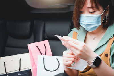 Close-up of woman wearing mask sitting with shopping bags in car