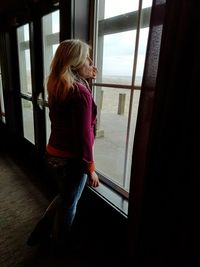 Mature woman looking through window at home