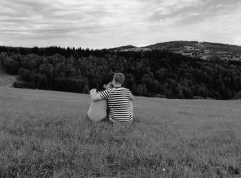 Rear view of couple sitting on grassy landscape