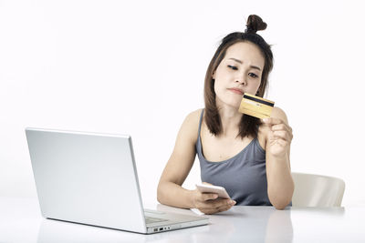 Young woman using phone while sitting on table