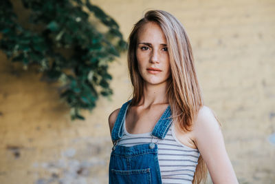 Portrait of young woman standing by wall