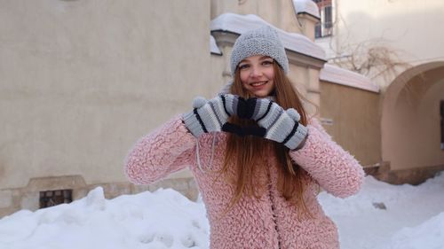 Portrait of smiling young woman standing in snow