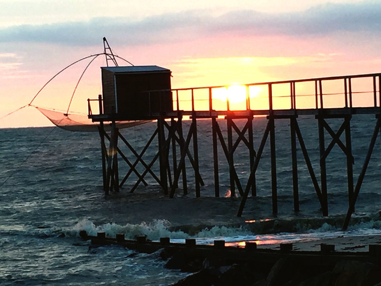 sunset, sea, built structure, water, cloud, dusk, scenics, architecture, sky, orange color, tranquil scene, tranquility, sun, rippled, building exterior, idyllic, coastline, nature, beauty in nature, dawn, lifeguard hut, outdoors, sunbeam, moody sky, calm, ocean, lifeguard, no people, cloud - sky, remote, majestic, dramatic sky