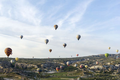 Hot air balloons flying over landscape against sky