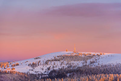 Scenic view of snow covered field against sky at sunset