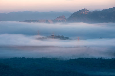 Transmission tower in green forest and beautiful smooth fog. energy and environment concept. 