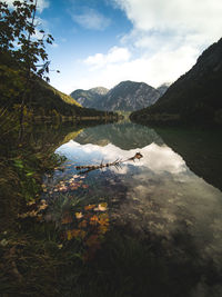 Scenic view of lake with autumn leaf against sky 