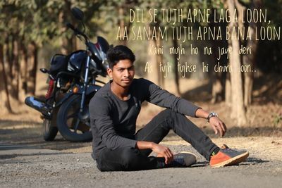 Portrait of young man sitting on road