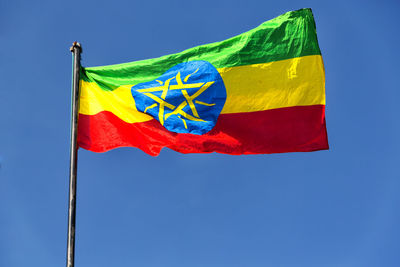 Low angle view of flag against blue sky