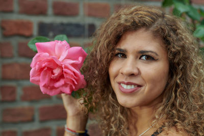 Close-up portrait of smiling woman with pink flower