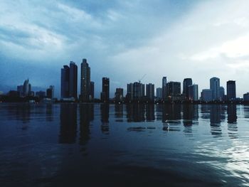 City skyline by river against sky