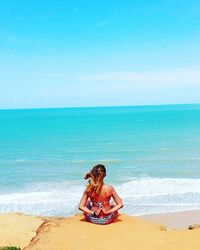 Rear view of woman sitting on beach