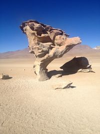Rock formation on field in desert against clear blue sky during sunny day