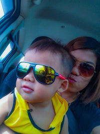 Tilt shot of woman and son wearing sunglasses in car