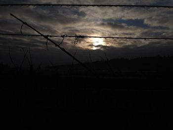 Silhouette of barbed wire against sky during sunset