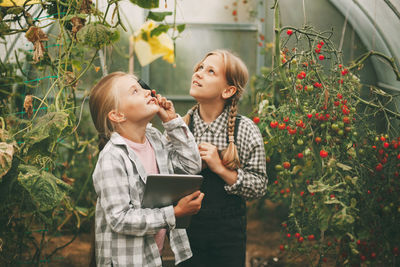 Happy friends smiling while holding plants