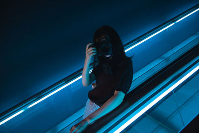 Low angle view of woman photographing through window